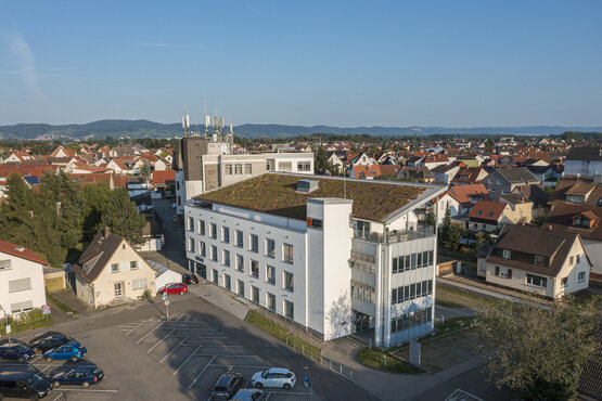 Luftaufnahme der Schön Klinik Lorsch mit begrüntem Flachdach, Parkplatz, umliegenden Wohnhäusern und grünen Hügeln im Hintergrund