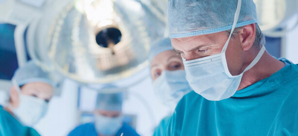 Chirurgenteam arbeitet konzentriert am Operationstisch im modernen OP-Saal, alle in OP-Kleidung und Masken