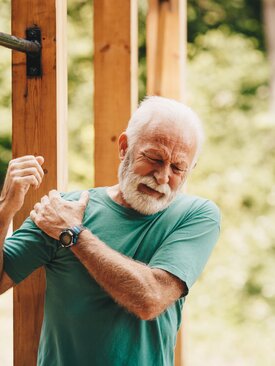 Älterer Mann hält sich schmerzhaft die Schulter, Symbolbild für Schulterschmerzen