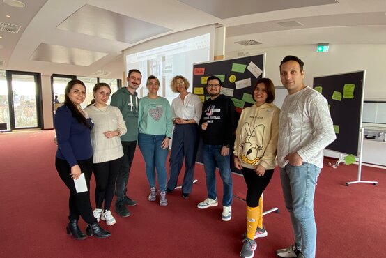 Acht Personen im Seminarraum vor Pinnwänden mit Notizzetteln