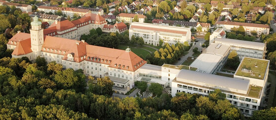Luftaufnahme der Schön Klinik München Harlaching mit historischen und modernen Gebäuden, roten Dächern und grüner Parklandschaft