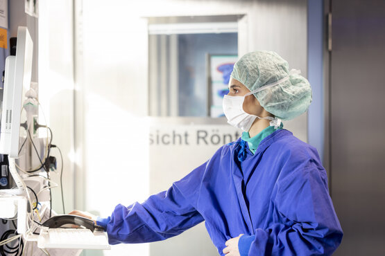 Medizinisches Fachpersonal in blauer Schutzkleidung bedient Computer im Krankenhaus