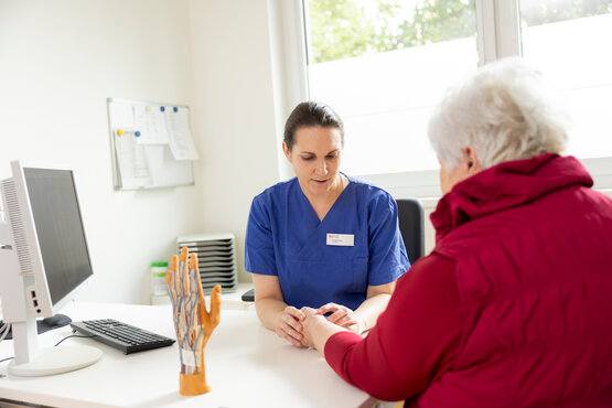 Ärztin im Gespräch mit Patientin, links Modell einer Hand