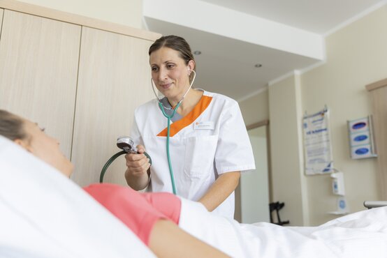 Pflegekraft misst Blutdruck bei Patient im Bett