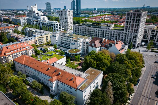 Luftaufnahme der Schön Klinik München Schwabing mit begrünten und roten Dächern und Bäumen