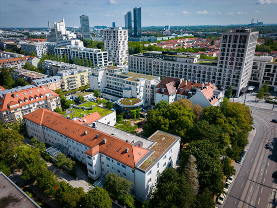 Luftaufnahme der Schön Klinik München Schwabing mit begrünten und roten Dächern und Bäumen