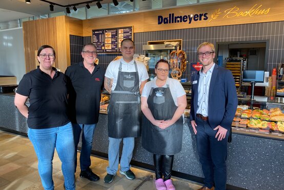 Fünf Personen vor Verkaufstheke mit belegten Brötchen und Backwaren, Schild „Dallmeyers Backhus“