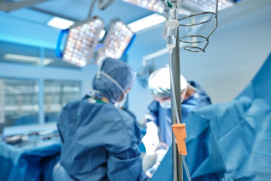 Ärzteteam in steriler OP-Kleidung operiert Patientin bei Skoliose im modernen Operationssaal