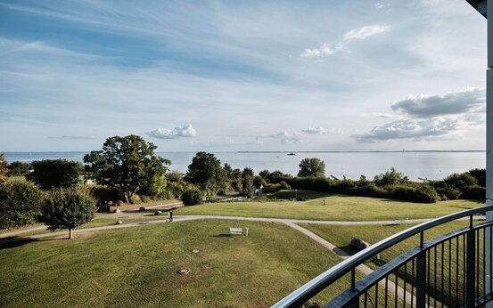 Blick vom Balkon aus einem Patientenzimmer auf grüne Wiese und Meer
