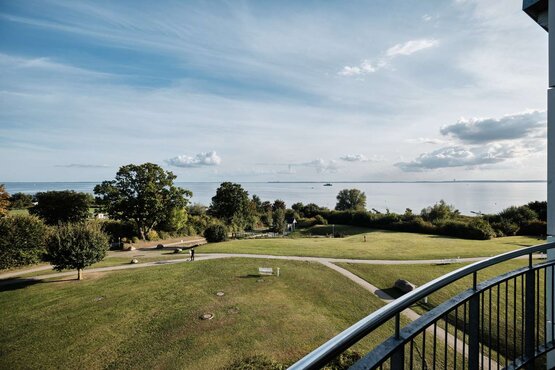 Blick vom Balkon aus einem Patientenzimmer auf grüne Wiese und Meer