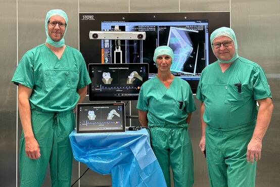 Drei medizinische Fachkräfte der Schön Klinik im Team stehen vor mehreren Monitoren