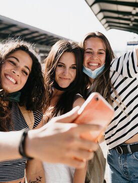 Drei glückliche Jugendliche machen ein Selfie am Bahnhof