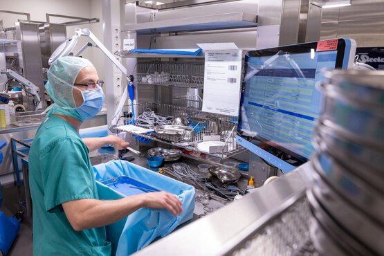 Mitarbeiter der Zentralsterilisation sortiert chirurgische Instrumente in Sieben