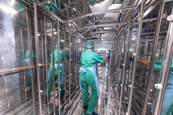 Mitarbeiterin mit Sterilisationswagen in Sterilisationskammer aus Edelstahl in der Zentralsterilisation