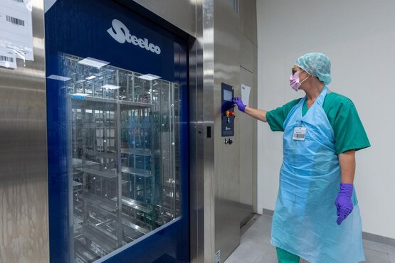 Mitarbeiterin der Zentralsterilisation bedient Reinigungs- und Desinfektionsgerät für Medizinprodukte