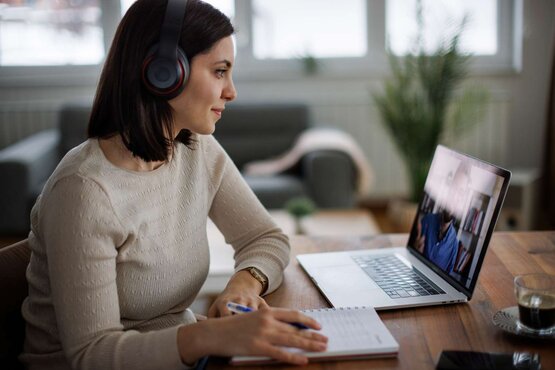 Frau verfolgt einen Online-Vortrag am Laptop