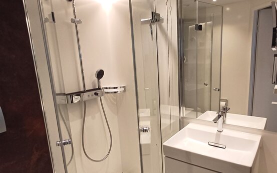 Modernes Bad der Schön Klinik Roseneck mit Glasdusche, Regenduschkopf, wandhängender Toilette und großem Spiegel