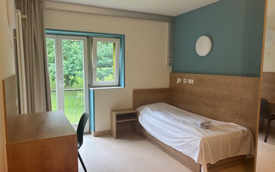 Helles Einzelzimmer mit Bett und Schreibtisch