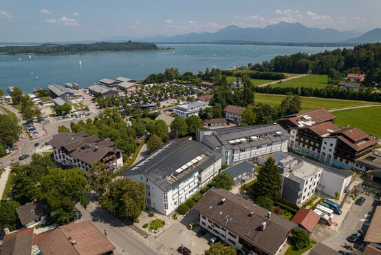 Luftaufnahme der Schön Klinik Roseneck vor dem Chiemsee mit Segelbooten, Alpenpanorama, Parkplatz und grüner Umgebung