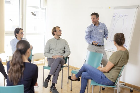 Klinikmitarbeiter präsentiert Diagramm am Flipchart vor Team im hellen Seminarraum