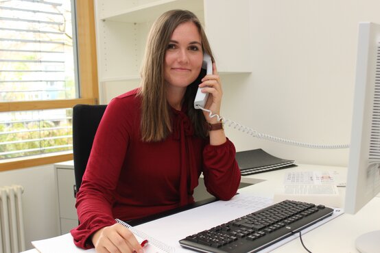 Franziska Müller Schlaganfall Kinderlotsin in dunkelroter Bluse, telefoniert am Schreibtisch