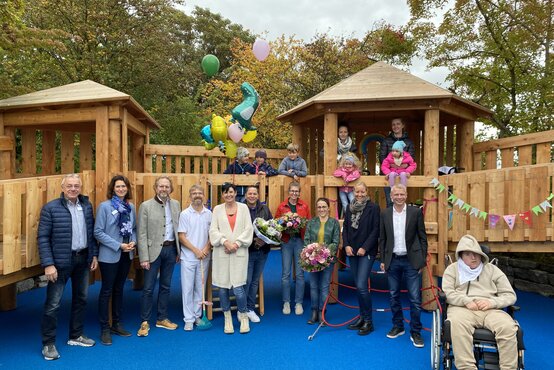 Spielplatzeröffnung an der Schön Klinik Vogtareuth mit Erwachsenen, Kindern – auch im Rollstuhl –, bunten Luftballons, Holzspielplatz