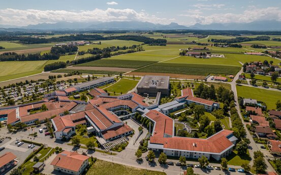Luftaufnahme der Schön Klinik Vogtareuth mit roten Ziegeldächern, grünen Höfen, Parkplätzen und umliegender ländlicher Landschaft