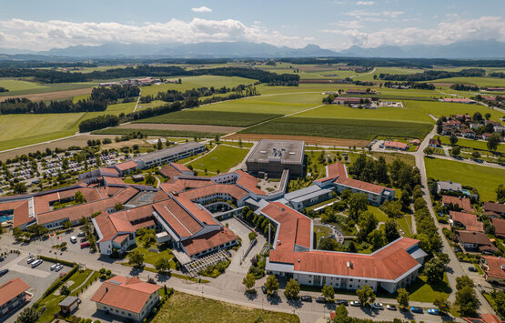 Luftaufnahme der Schön Klinik Vogtareuth mit roten Ziegeldächern, grünen Höfen, Parkplätzen und umliegender ländlicher Landschaft