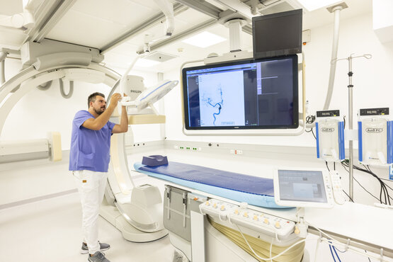 Klinik Radiologie Raum mit moderner Angiographie-Anlage, Monitor und medizinischem Personal