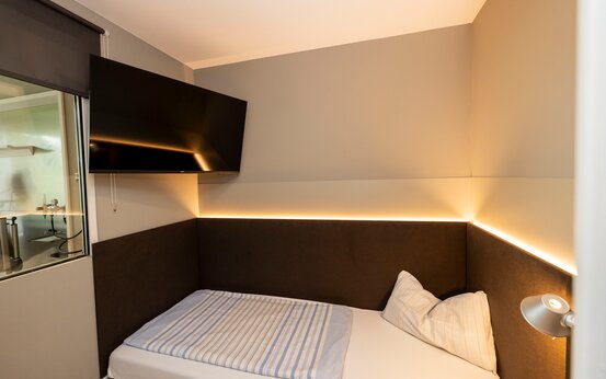 Zimmer der Schön Klinik Vogtareuth mit Einzelbett, LED-Beleuchtung, Flachbildfernseher, Leselampe und Glasfenster zu weiterem Bereich