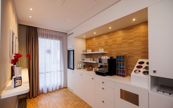 Patientenküche der Schön Klinik Vogtareuth mit hellem Holzfußboden, Fenstern, Kaffee- und Teestation