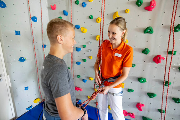 Therapeutin und Patient bei der Klettereinweisung an der Indoor-Kletterwand