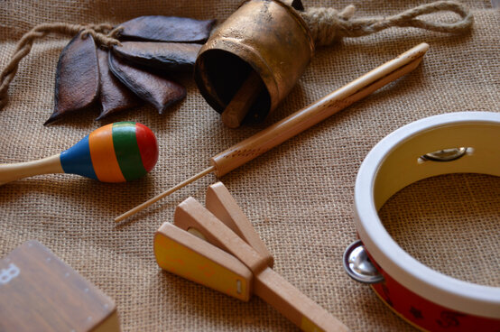 Rhythmusinstrumente wie bunte Maracas, Tamburin, Claves, Agogo, Schellen und Samenrassel auf Juteunterlage für Musiktherapie