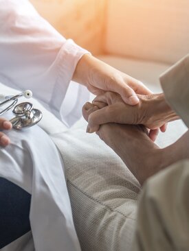 Arzt untersucht und hält fürsorglich den Fuß eines Patienten bei Verdacht auf Fußwurzelbruch