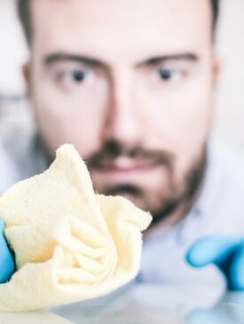 Einweghandschuhen desinfiziert glatte Oberfläche gründlich mit gelbem Tuch, Fokus auf Hygiene