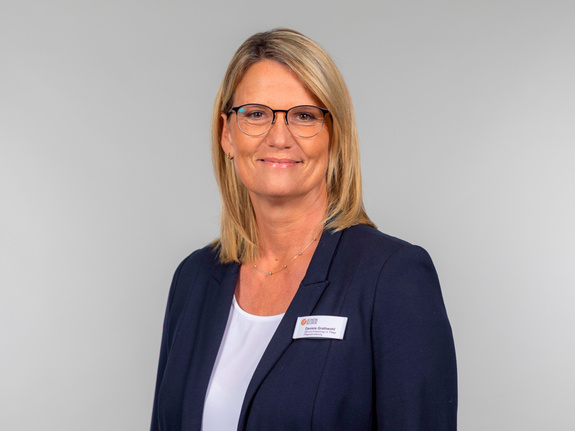 Porträt von Daniela Grathwohl, Pflegedienstleiterin der Schön Klinik Vogtareuth, mit Brille und kurzem Haar vor neutralgrauem Hintergrund