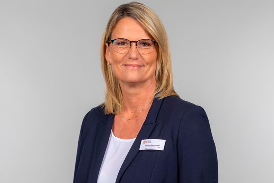 Porträt von Daniela Grathwohl, Pflegedienstleiterin der Schön Klinik Vogtareuth, mit Brille und kurzem Haar vor neutralgrauem Hintergrund