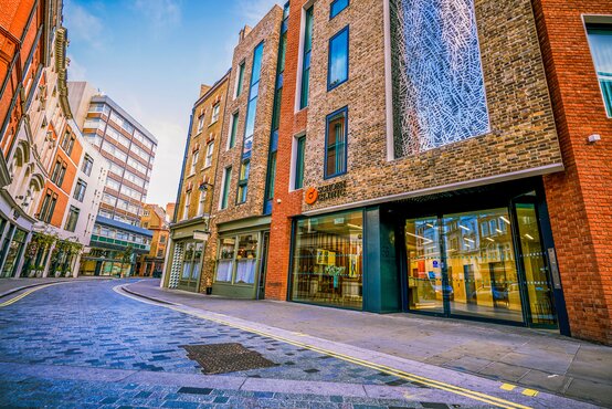 Leere Stadtstraße mit Gebäude der Schoen Clinic London, Schaufenster, Pflanzenkästen, blauer Himmel