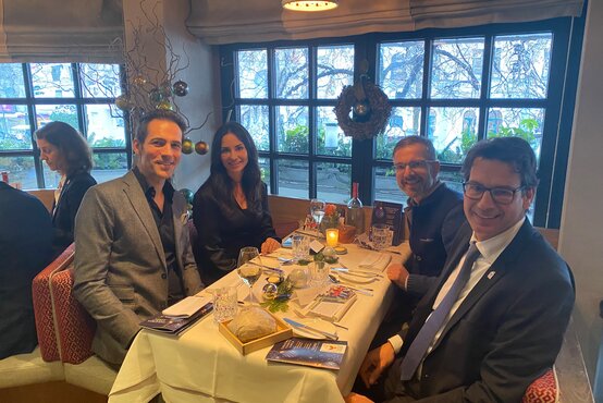 Vier elegant gekleidete Personen beim Charity Brunch an festlich gedecktem Tisch