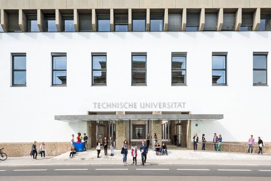Helle Fassade mit Schriftzug „Technische Universität“, moderne Fenster, Menschen vor dem Eingang