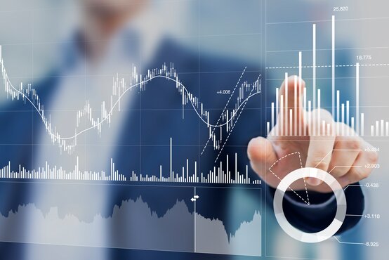 Geschäftsmann im Anzug tippt auf digitales Interface mit Diagrammen und Kennzahlen für Controlling und Datenanalyse