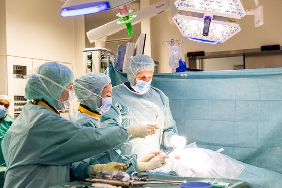 Chirurgen und medizinisches Team führen Operation im modernen OP-Saal mit Medizintechnik und OP-Leuchte durch