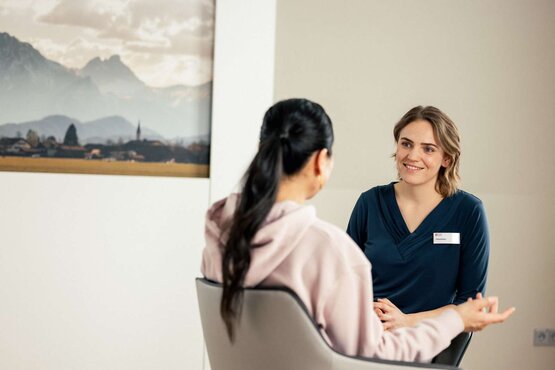 Junge Ärztin im Beratungsgespräch mit patienten in hellem Klinik Raum