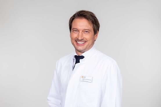 Prof. Dr. Rembert Koczulla. Mann mit kurzen braunen Haaren im weißen Arztkittel und Krawatte