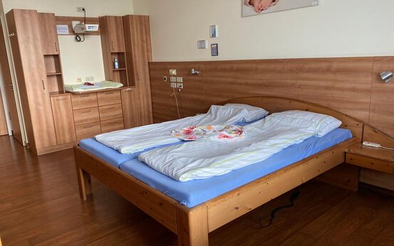 Helles Zimmer mit Holzboden, Doppelbett mit blauer Matratze, Wickelauflage, Nachttisch