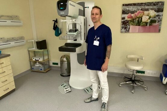 Mann in blauer Arbeitskleidung steht in modernem Mammographie-Untersuchungsraum der Schön Klinik Rendsburg