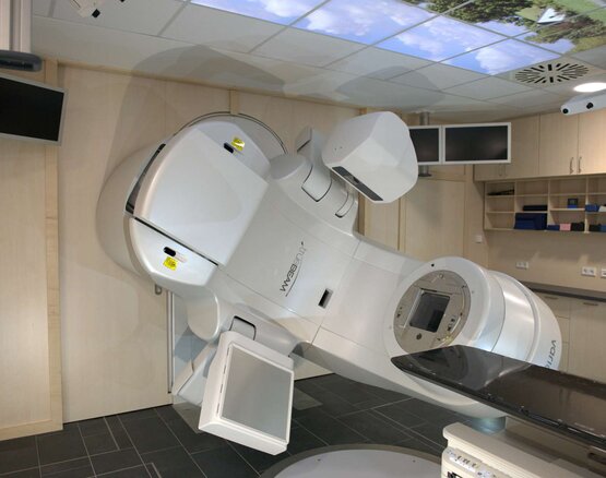 Linearbeschleuniger für Strahlentherapie in modernem Behandlungsraum der Schön Klinik Rendsburg, Liegefläche und Monitore sichtbar