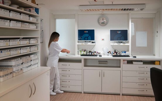 Heller, moderner Medikamentenraum mit medizinischem Fachpersonal, Computerarbeitsplätzen und beschrifteten Medikamentenschränken